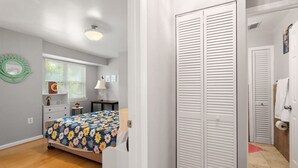 A bedroom with a bed, a dresser, a nightstand, and a closet.