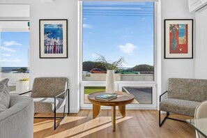 A modern living room with two patterned armchairs, a wooden coffee table, and framed artwork on the walls.
