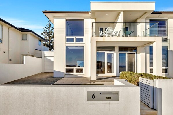 A modern two-story house with large windows, a balcony, and a number 6 sign. - Sunset Sands on Esplanade | By Host Solutions (West Beach)