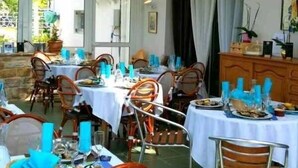 Un área de comedor al aire libre con mesas y sillas, una zona cubierta con techo y vistas hacia el exterior.