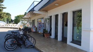 Un bâtiment doté d’une entrée abritée, avec des vélos garés à l’extérieur et un pot de fleurs placé sur le trottoir.