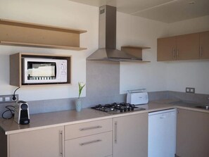 A modern kitchen with a microwave, stove, and dishwasher. - ZEcamping 4 étoiles toboggans locatif TV LV clim 54m2 (Regencós)