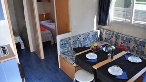 A compact RV interior with a dining area, a kitchenette, and a sleeping space.