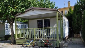 A small, single-story mobile home with a porch and two bicycles parked in front.
