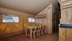 Un interior de madera con una mesa y sillas de comedor, ventanas amplias y techo de madera.