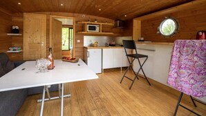 A compact cabin interior with a dining area, kitchenette, and a cozy seating space. - ZEcamping 3 étoiles piscine couverte animaux acceptés locatif clim (Chamberet)