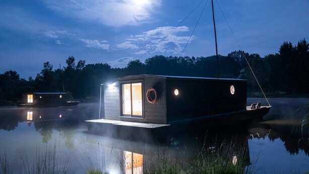 A houseboat with a small cabin and a covered deck, floating on calm water with a reflection of the moon and trees in the background. - ZEcamping 3 étoiles piscine couverte animaux acceptés locatif clim (Chamberet)
