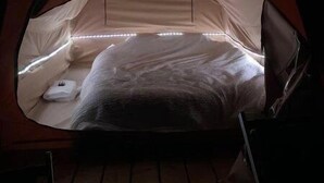 Ein gemütlicher, rund geformter Zeltraum mit einem Bett, einem kleinen Tisch und einer Bank.