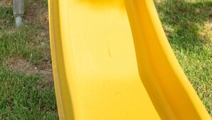 Ein Kind rutscht auf einer gelben Rutsche in einem Park.