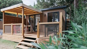 A wooden cabin with a covered porch and a fenced-in area.