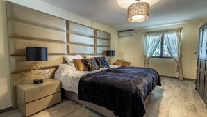 A modern bedroom with a large bed, a nightstand, a lamp, and a window with curtains. - Fantastic 7-bed Villa in Alhaurin de la Torre (Alhaurin de la Torre)