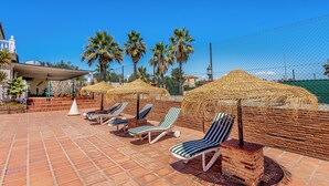 A rooftop terrace with lounge chairs, thatched umbrellas, and palm trees. - Fantastic 7-bed Villa in Alhaurin de la Torre (Alhaurin de la Torre)
