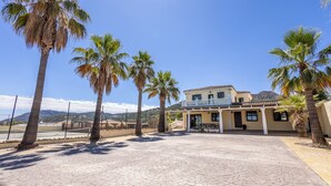 A building with a tiled courtyard, palm trees, and a clear blue sky. - Fantastic 7-bed Villa in Alhaurin de la Torre (Alhaurin de la Torre)