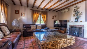A living room with a leather sofa, a glass coffee table with logs, a fireplace, and a TV. - Fantastic 7-bed Villa in Alhaurin de la Torre (Alhaurin de la Torre)
