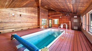 A wooden cabin with a pool, wooden walls, and a wooden deck.