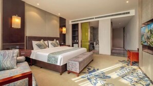 Ein modernes Hotelzimmer mit einem großen Bett, einer Couch, einer Bank und einem Fernseher.