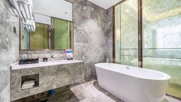 Une salle de bain moderne avec une baignoire sur pieds, des murs en marbre et un grand miroir.