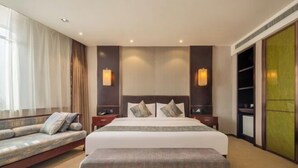 Ein Hotelzimmer mit einem großen Bett, einer Couch, einer Bank und einem Kleiderschrank.