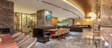 A modern hotel lobby with a curved ceiling, marble flooring, and a bar area.