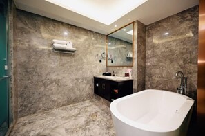 A modern bathroom with a freestanding bathtub, marble walls, a vanity with a mirror, and a towel rack. - Asia Europe Hotel (Lan Da Er Yuan Branch, Xiguan Metro Station) (Lanzhou)