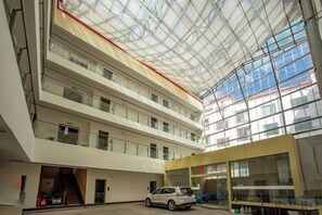 Un atrio a più livelli con soffitto in vetro, diversi piani e un'auto parcheggiata al livello inferiore.