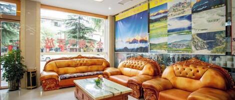 A spacious lobby with leather sofas, a marble coffee table, and large windows offering a view of the outdoors.