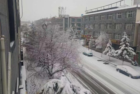 A snowy urban street with buildings and bare trees. - Yutong Holiday Hotel (Shangri-La)