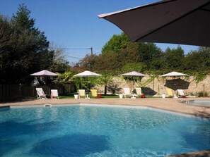 Piscina com espreguiçadeiras e guarda-sóis.