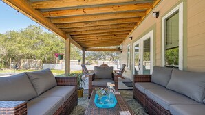A covered patio area with wicker furniture, a coffee table, and a view of the backyard.
