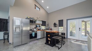 A modern kitchen with a central island, stainless steel appliances, and a small window.
