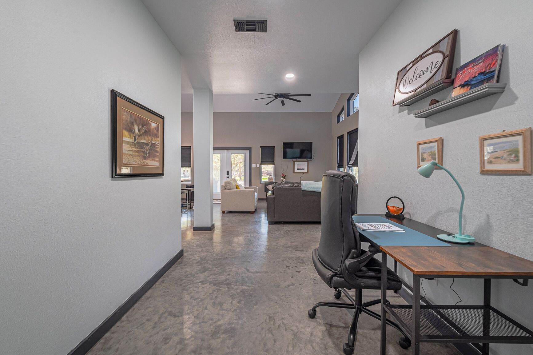 A hallway with a desk, chair, and artwork on the walls.