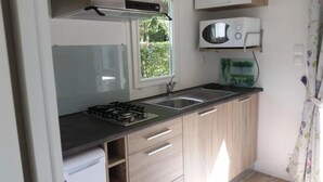 Una cocina compacta con estufa a gas, microondas y ventana.