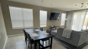 A spacious living room with a dining area, large windows, a flat-screen TV, and a grey sofa. - Spacious, Family-Friendly Home in Maricopa (Maricopa)