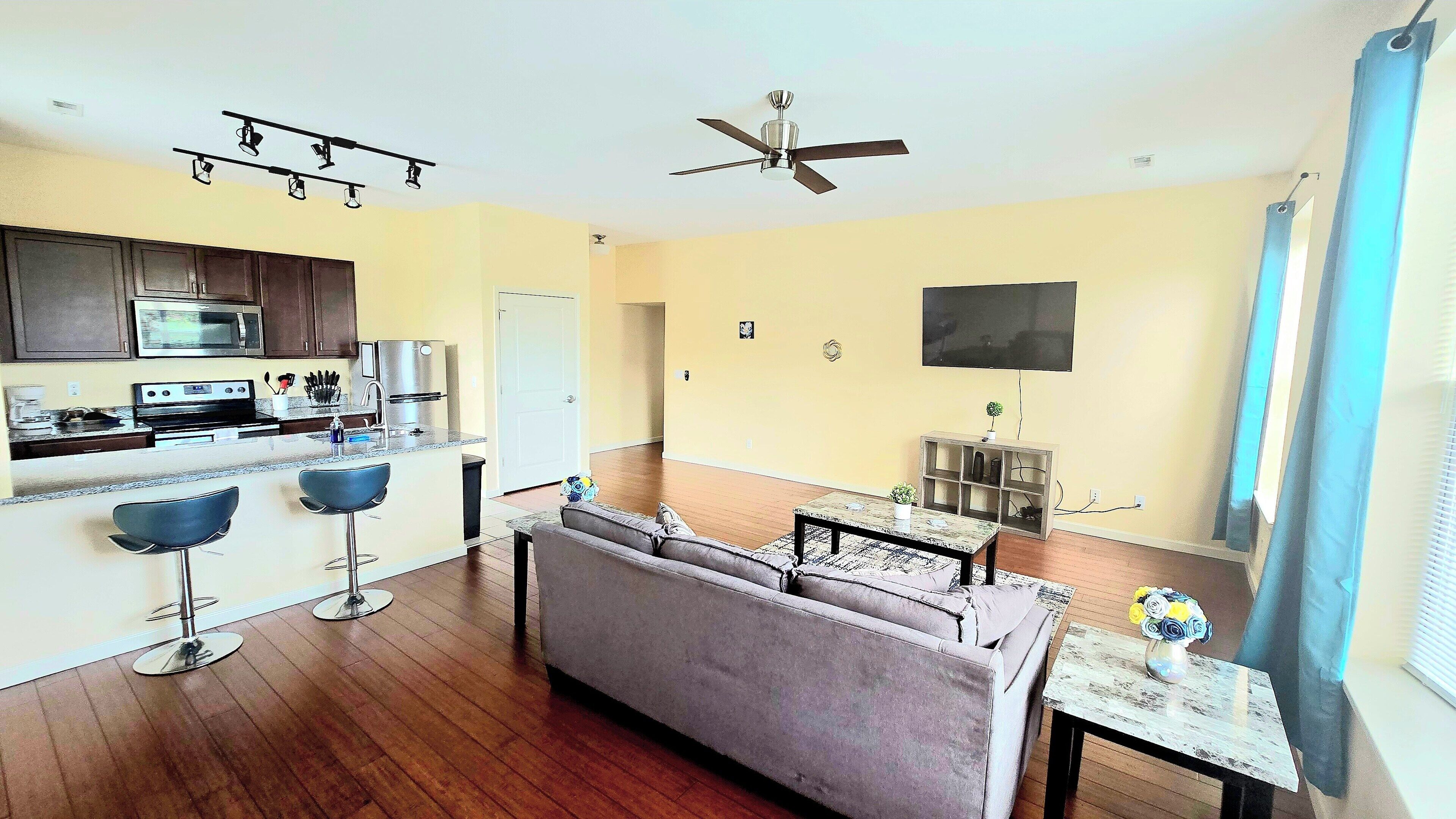 A compact living space with a kitchenette, a sofa, a dining table, and a ceiling fan.