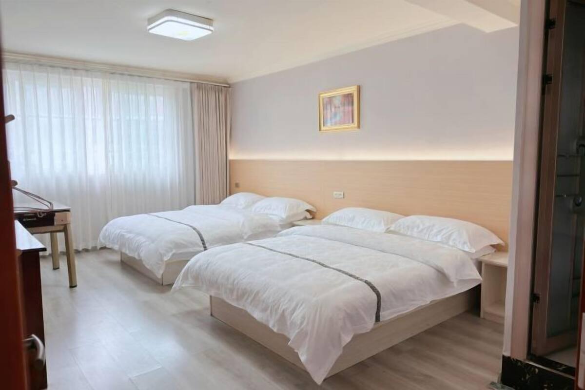 Een hotelkamer met twee bedden, een bureau en een lijst aan de muur.