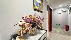 A hallway with a marble console table holding a vase of orchids.
