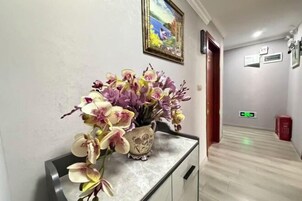 Um corredor com um aparador de mármore e um vaso de orquídeas.