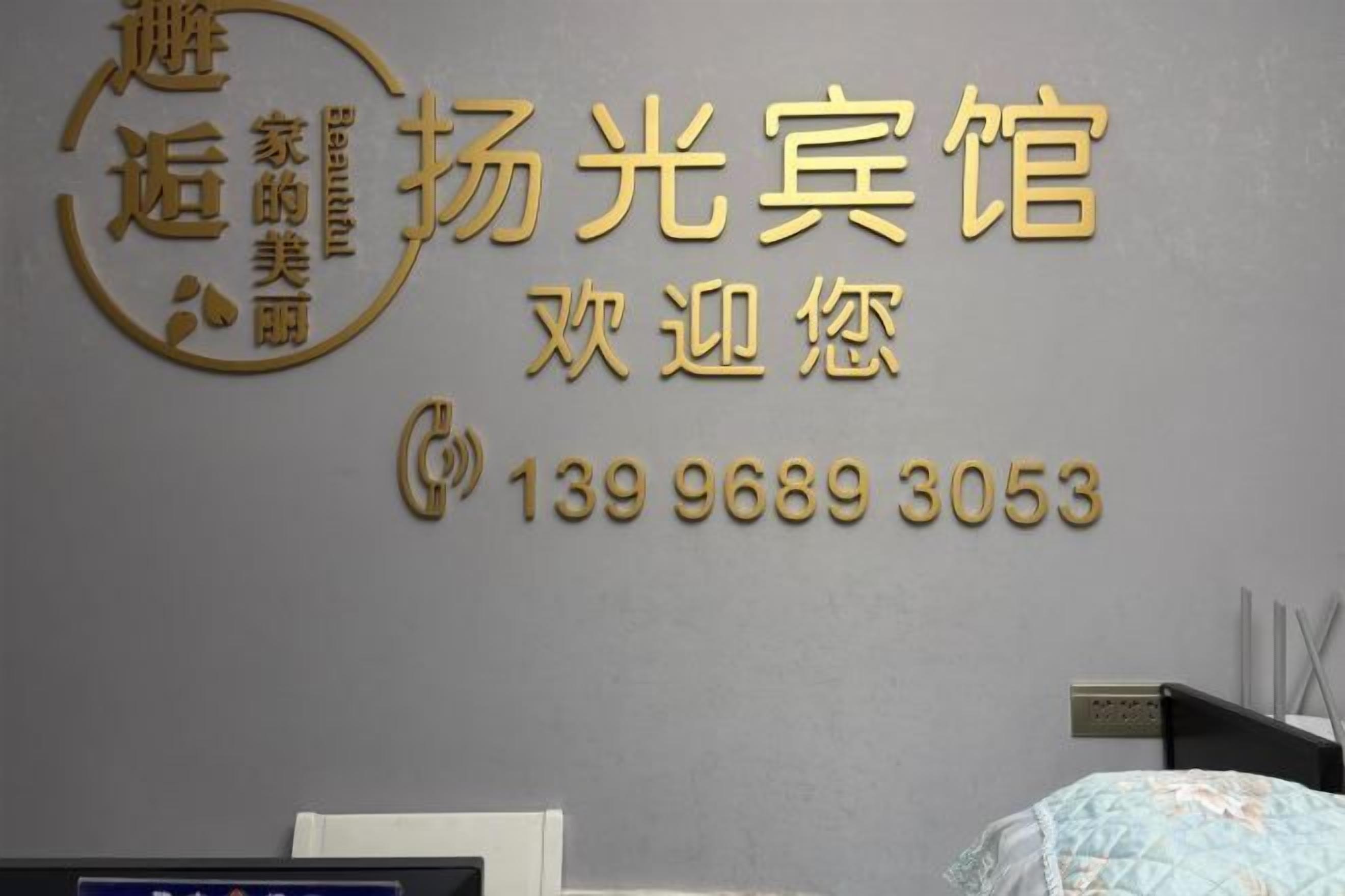 A hotel sign with the name 'Yang Guang Bing' and a phone number.