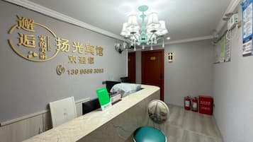 A reception area with a marble counter, a chandelier, and a wall-mounted sign.