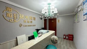 A reception area with a marble counter, a green sign, a chandelier, and fire extinguishers.