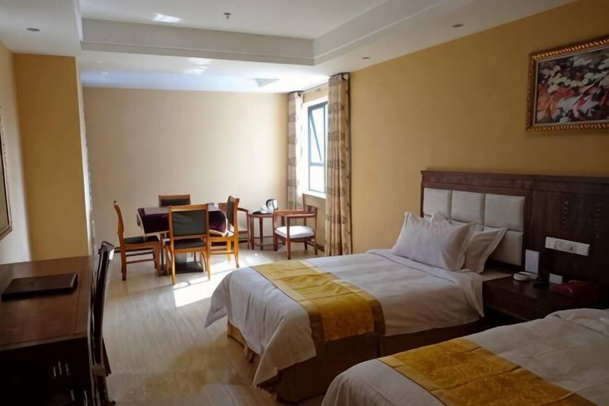 Habitación de hotel con dos camas, un escritorio, una silla y un cuadro en la pared.