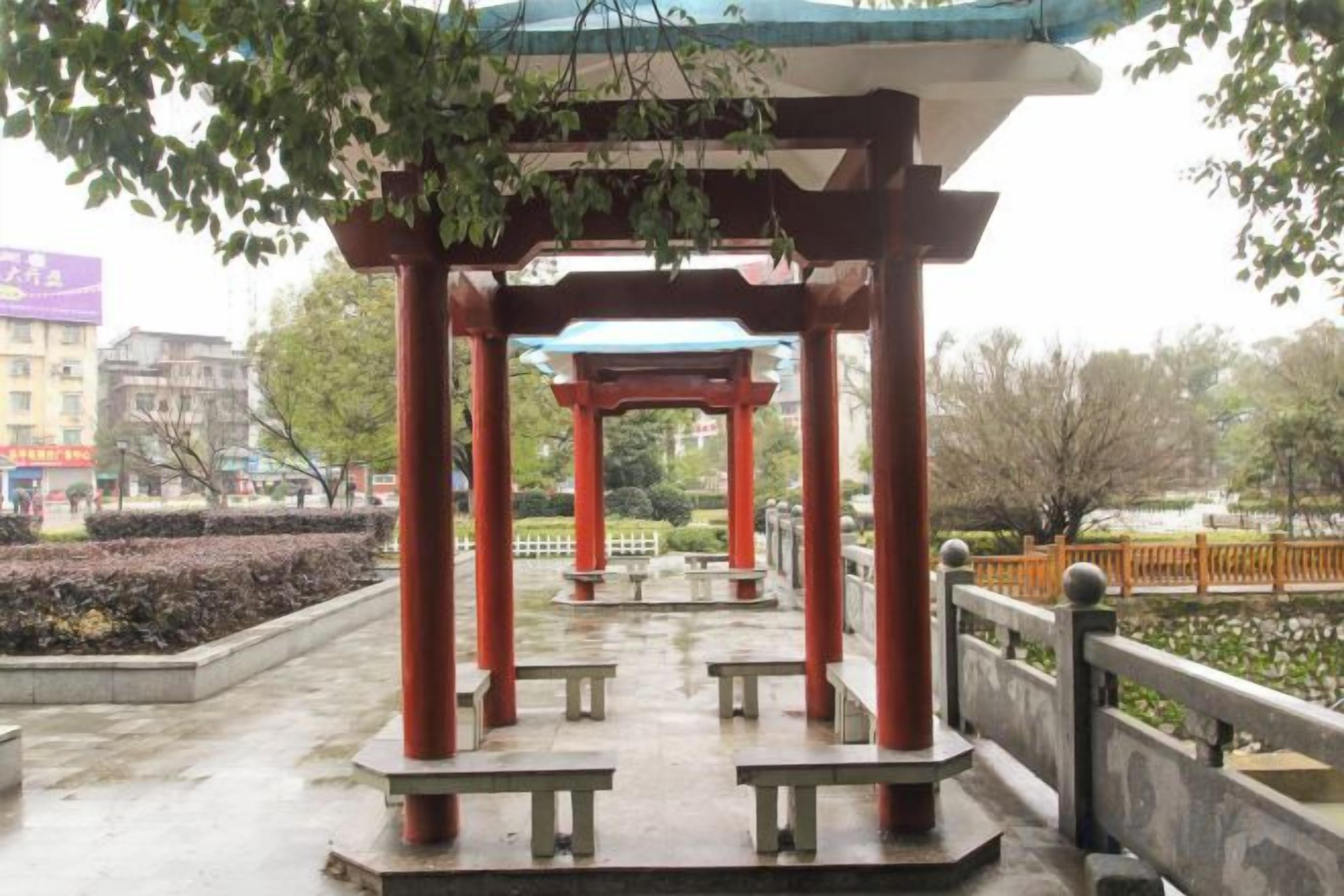 A traditional Japanese pavilion with a roof, benches, and a stone pathway.
