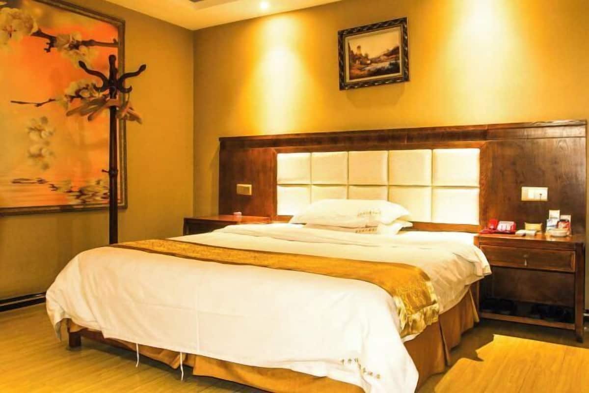 Habitación de hotel con una cama grande, cabecera de madera, mesitas de noche y un cuadro en la pared.