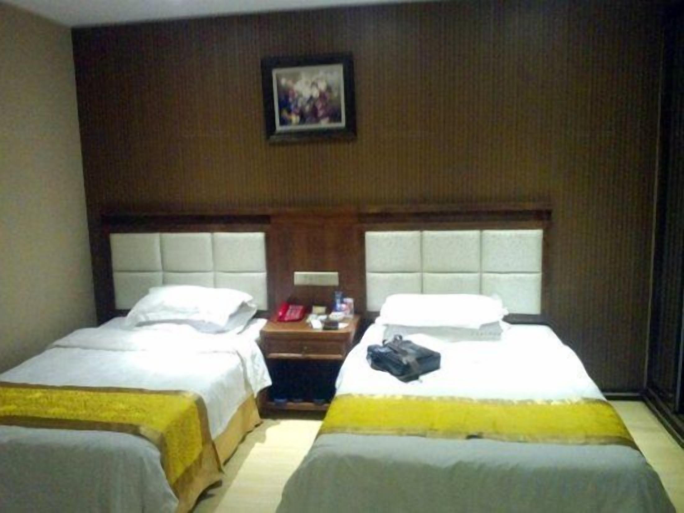 A hotel room with two beds, a nightstand, and a framed picture on the wall.