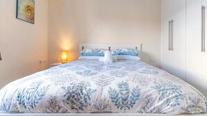 A bedroom with a bed, nightstand, wall art, and a wardrobe. - Lovely Two Bed detached house with Parking (Tipton)