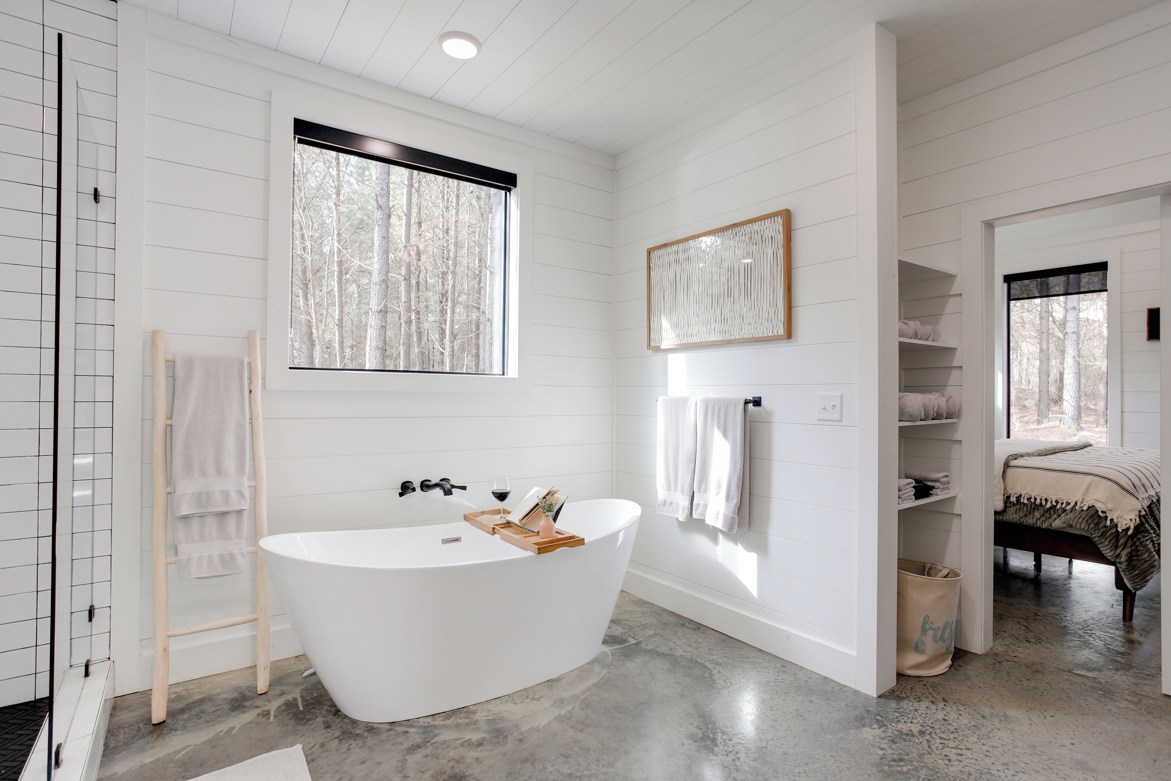 Une salle de bain moderne avec une baignoire sur pieds, une échelle en bois et une grande fenêtre qui laisse entrer la lumière naturelle.