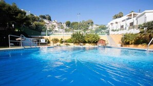En swimmingpool med krystalklart, blåt vand, omgivet af et hegn og nogle få træer.