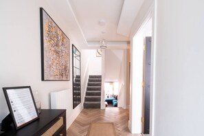 Ein Flur mit einer Treppe, einem gerahmten Kunstwerk und einem Schild auf einem Tisch.