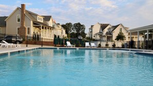A swimming pool with lounge chairs, surrounded by houses.