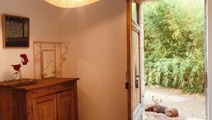 Ein Holzkabinent mit einer Vase voller roter Blumen, einer Pendelleuchte und einer Tür, die in einen Garten führt.